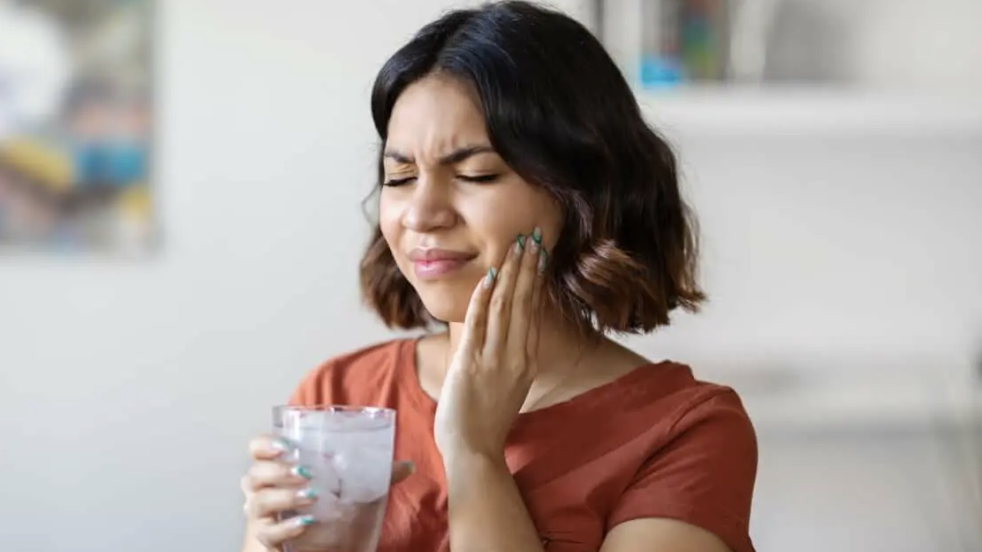 persona notando una molestia en un diente después de beber un vaso de agua